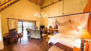 A spacious room with a bed, a desk, a chair, and a dining table. - Kumbali Country Lodge (Lilongwe)