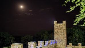 A stone tower with a narrow entrance, surrounded by a stone wall with blue lights. - Kumbali Country Lodge (Lilongwe)