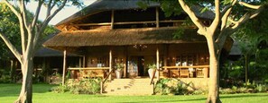 A two-story building with a thatched roof, surrounded by lush greenery. - Kumbali Country Lodge (Lilongwe)