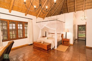 A bedroom with a four-poster bed, a wooden chest, a nightstand, and a bedside table. - Kumbali Country Lodge (Lilongwe)