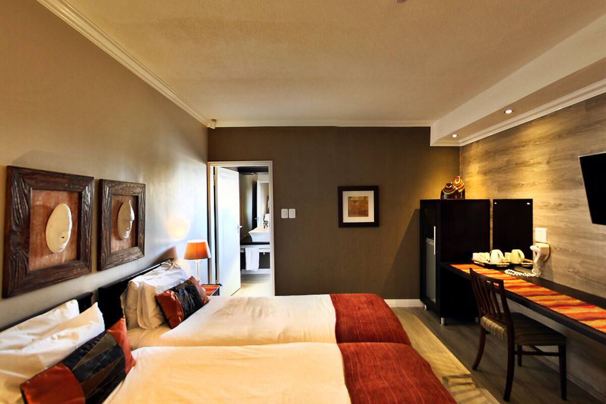 Una habitación de hotel con dos camas, un escritorio, una silla y un televisor.