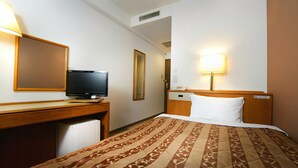 A hotel room with a bed, a desk with a television, a bedside lamp, and a mirror. - Bells's Inn Maebashi (Maebashi)