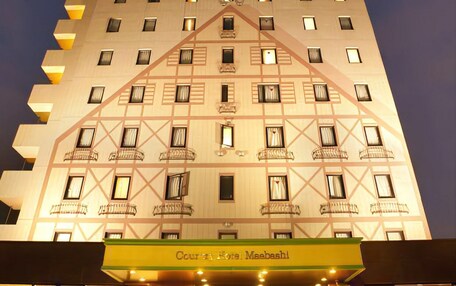 A hotel with a modern design, featuring a prominent entrance with a yellow awning and a sign that reads "Couran Hotel Msebash."