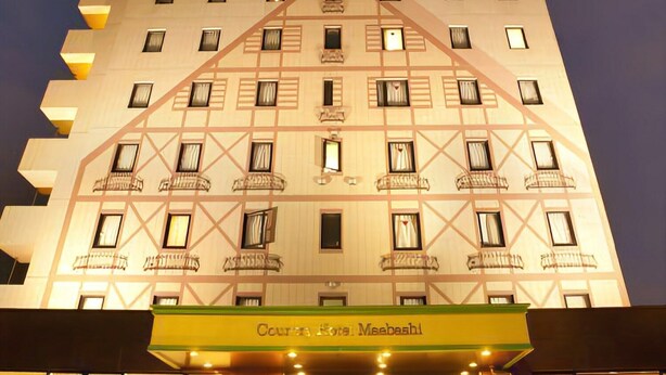A hotel with a modern design, featuring a prominent entrance with a yellow awning and a sign that reads "Couran Hotel Msebash." - Bells's Inn Maebashi (Maebashi)