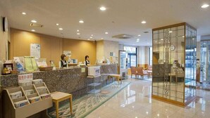 A hotel reception area with a counter, seating, and a decorative glass partition. - Bells's Inn Maebashi (Maebashi)