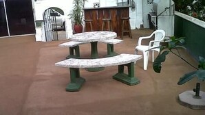 A patio area with two marble-top tables and chairs, a potted plant, and a wooden fence. - The Troll and Tulip (Durban)