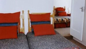 A room with two single beds with wooden frames and red and blue bedding. - The Troll and Tulip (Durban)