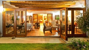 Ein offener Wohnbereich mit einer Holzpergola, Schiebeglasfenstern und einem Fliesenboden.