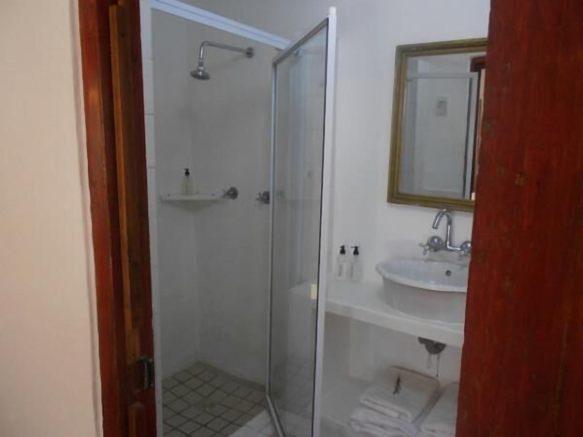 Un bagno con cabina doccia in vetro, lavandino e specchio.
