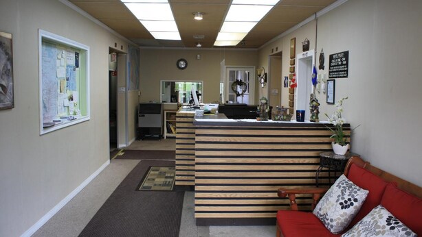 Een receptie met een houten balie, een rode bank en een klok aan de muur.