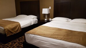Een hotelkamer met twee bedden, elk met een bruine deken en witte lakens. Tussen de bedden staat een nachtkastje met een lamp en een telefoon.