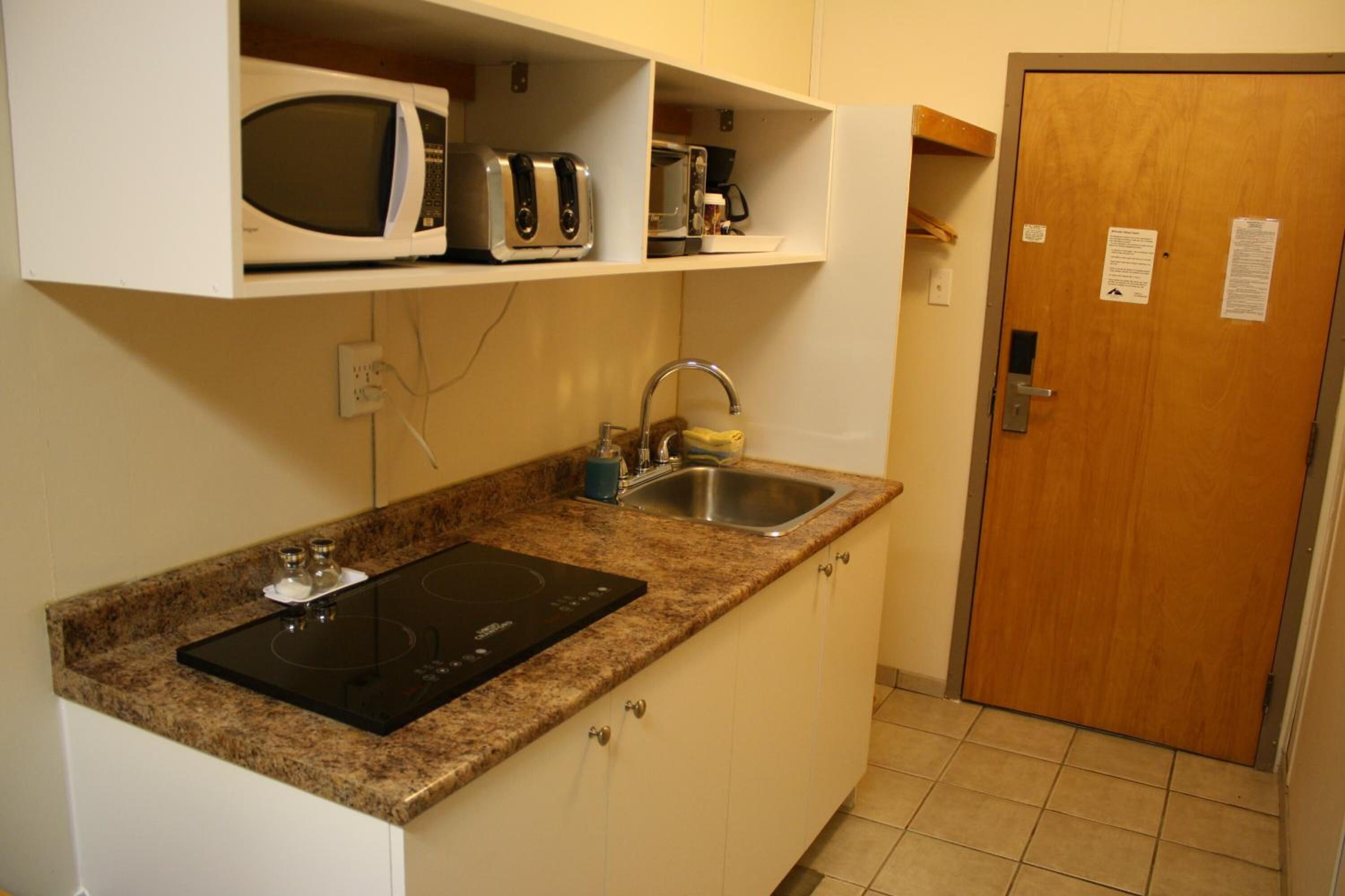 A compact kitchen with a built-in microwave, toaster, and sink.