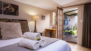 Habitación de hotel con cama, lámpara, una mesita y vista al patio exterior.