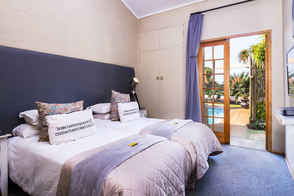 A hotel room with a large bed, a desk, and a view of the outdoor pool area.