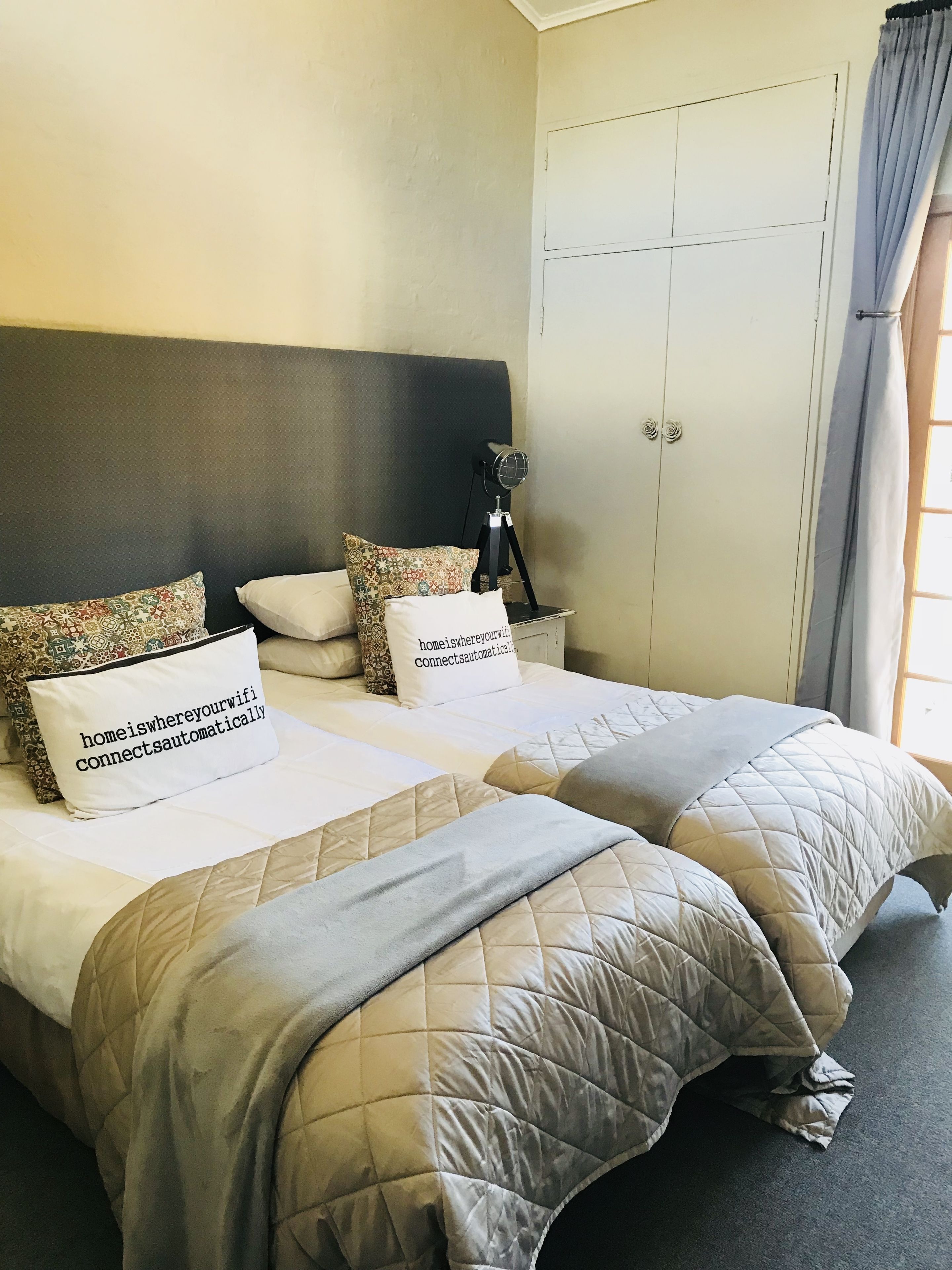 A hotel room with two beds, each with a quilted bedspread and pillows, including one with a message about WiFi.