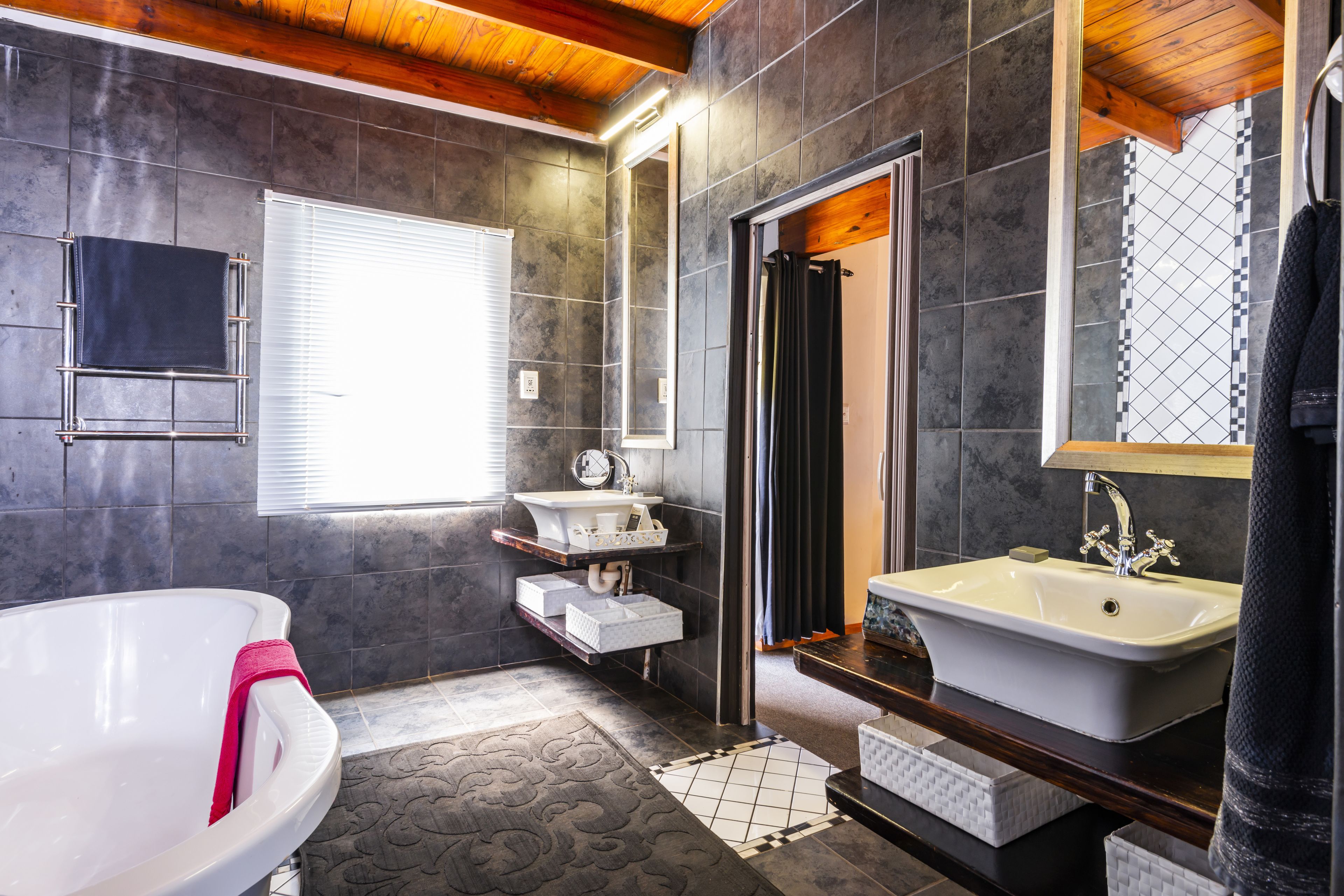 Un baño moderno con una bañera independiente, un tocador con lavabo y un espejo grande.