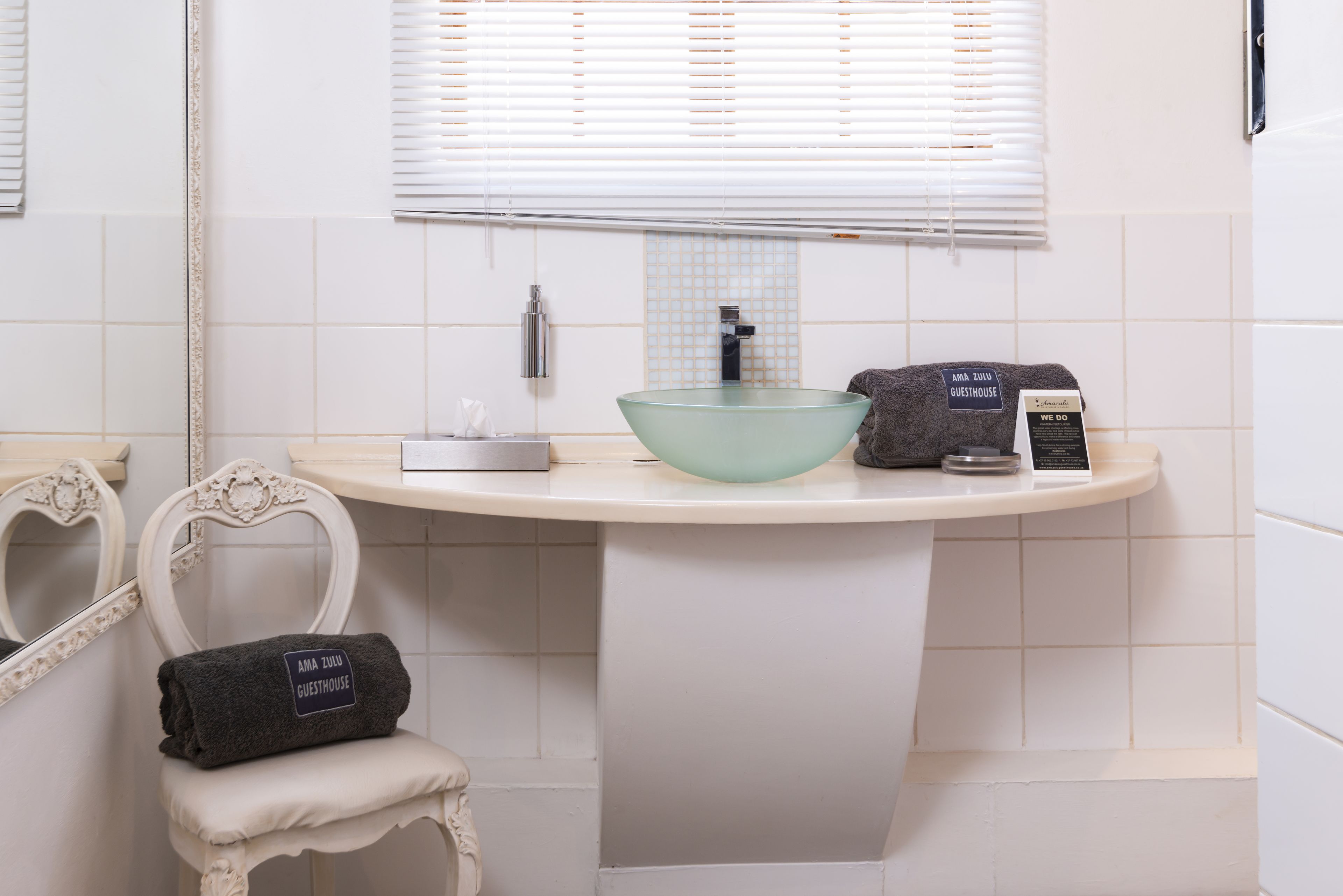Une salle de bain avec un meuble-lavabo blanc, un lavabo en forme de bol en verre, un porte-serviettes et un miroir.