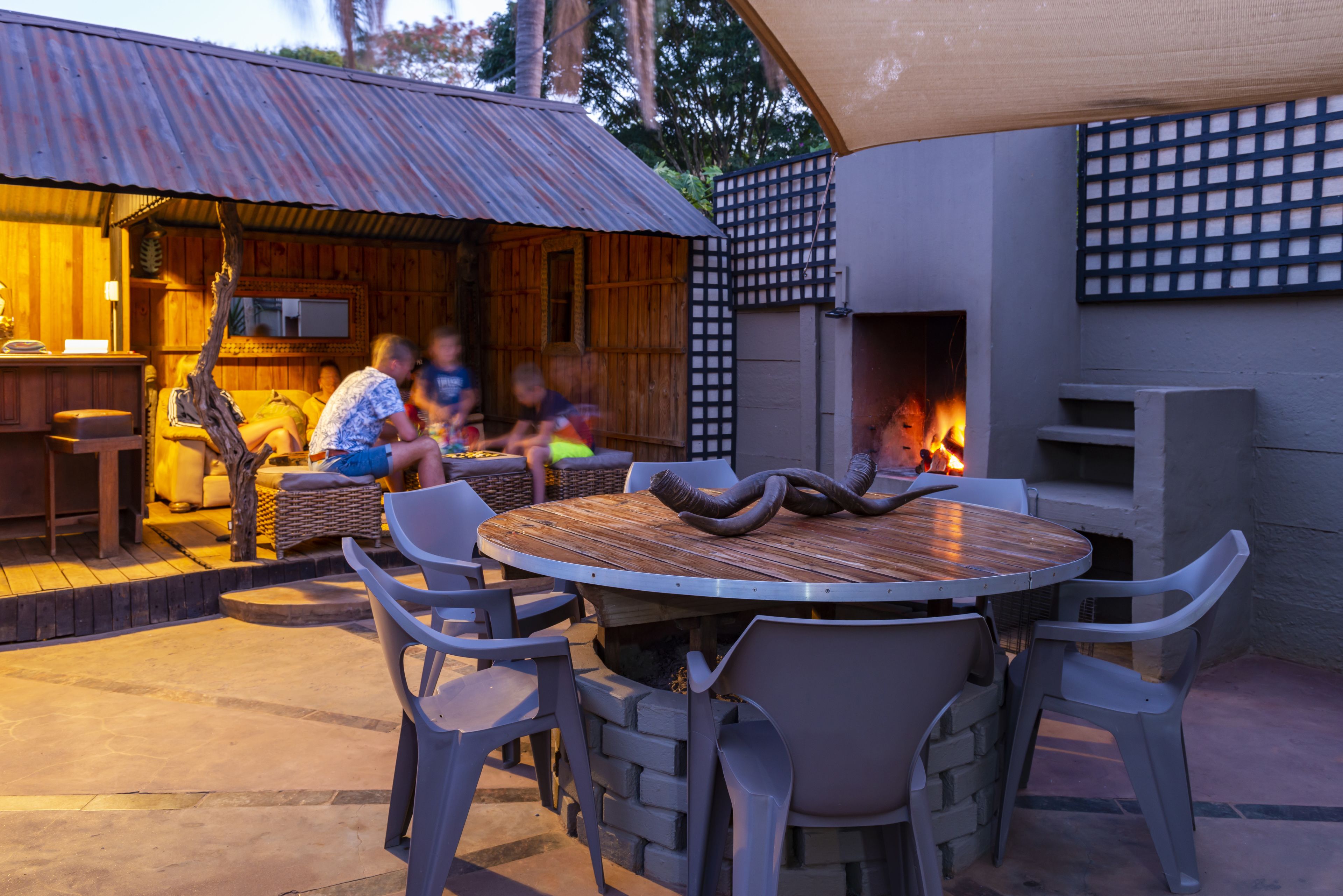 Une terrasse extérieure avec une table ronde, des chaises et un foyer.