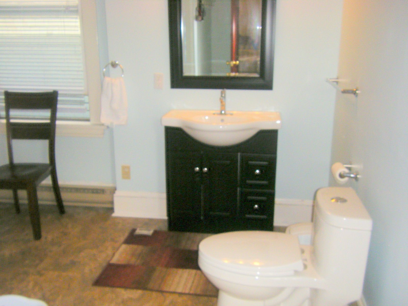 A bathroom with a toilet, sink, and mirror.