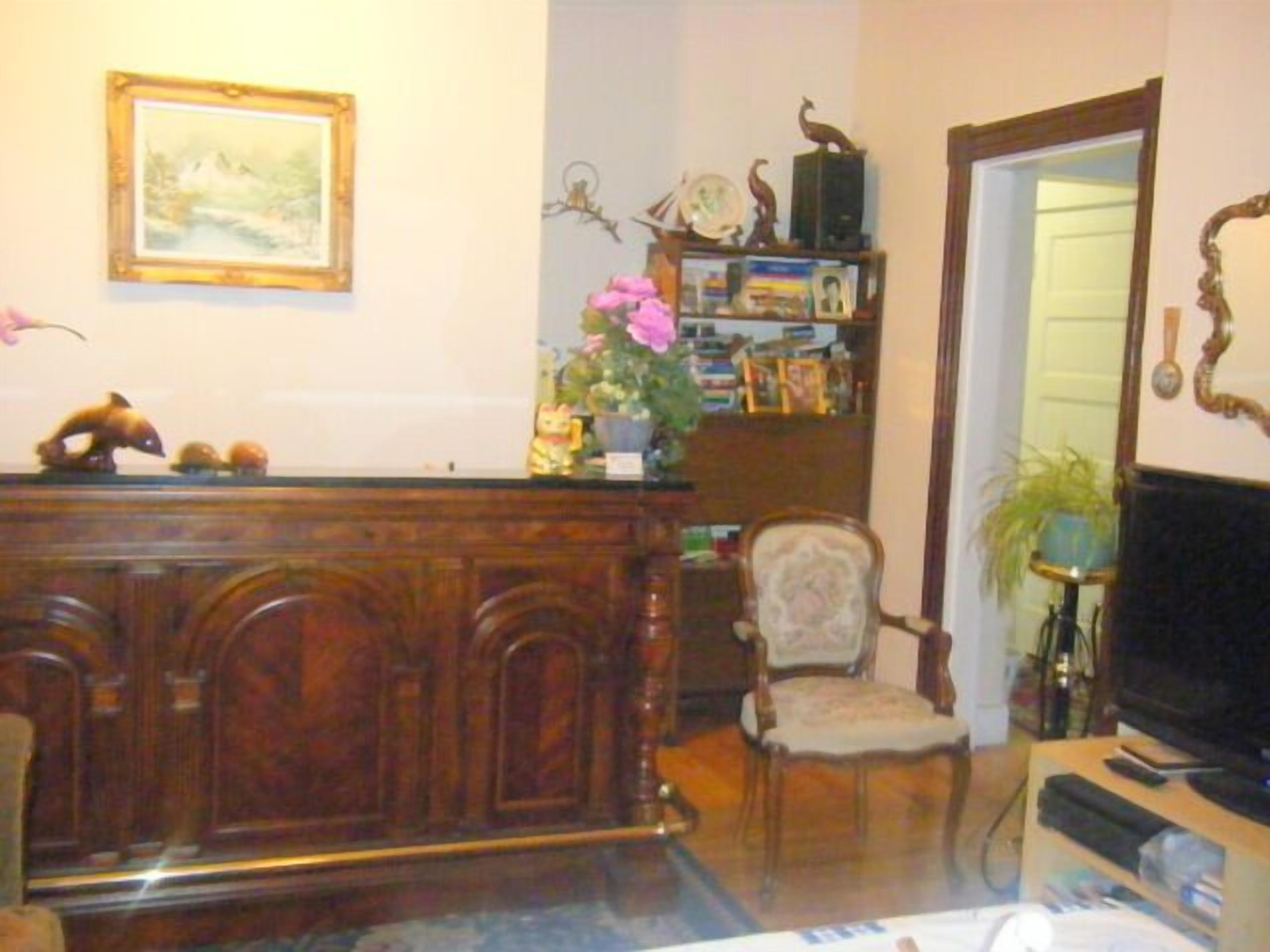 A living room with a wooden cabinet, a television, a chair, and a bookshelf.