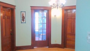A hallway with wooden doors, a framed picture on the wall, and a chandelier.