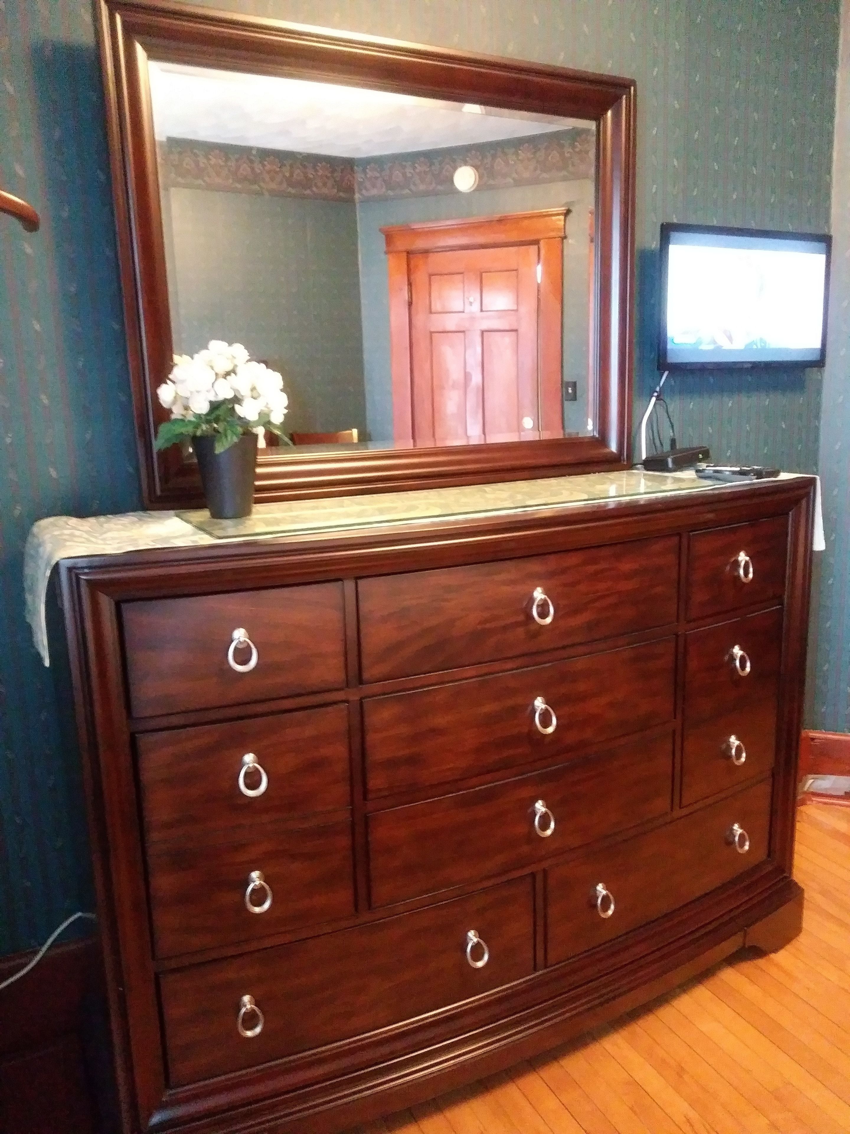 A wooden dresser with multiple drawers and a large mirror above it.
