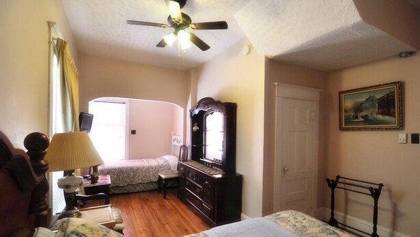 A bedroom with two beds, a dresser, a mirror, a ceiling fan, and a door.