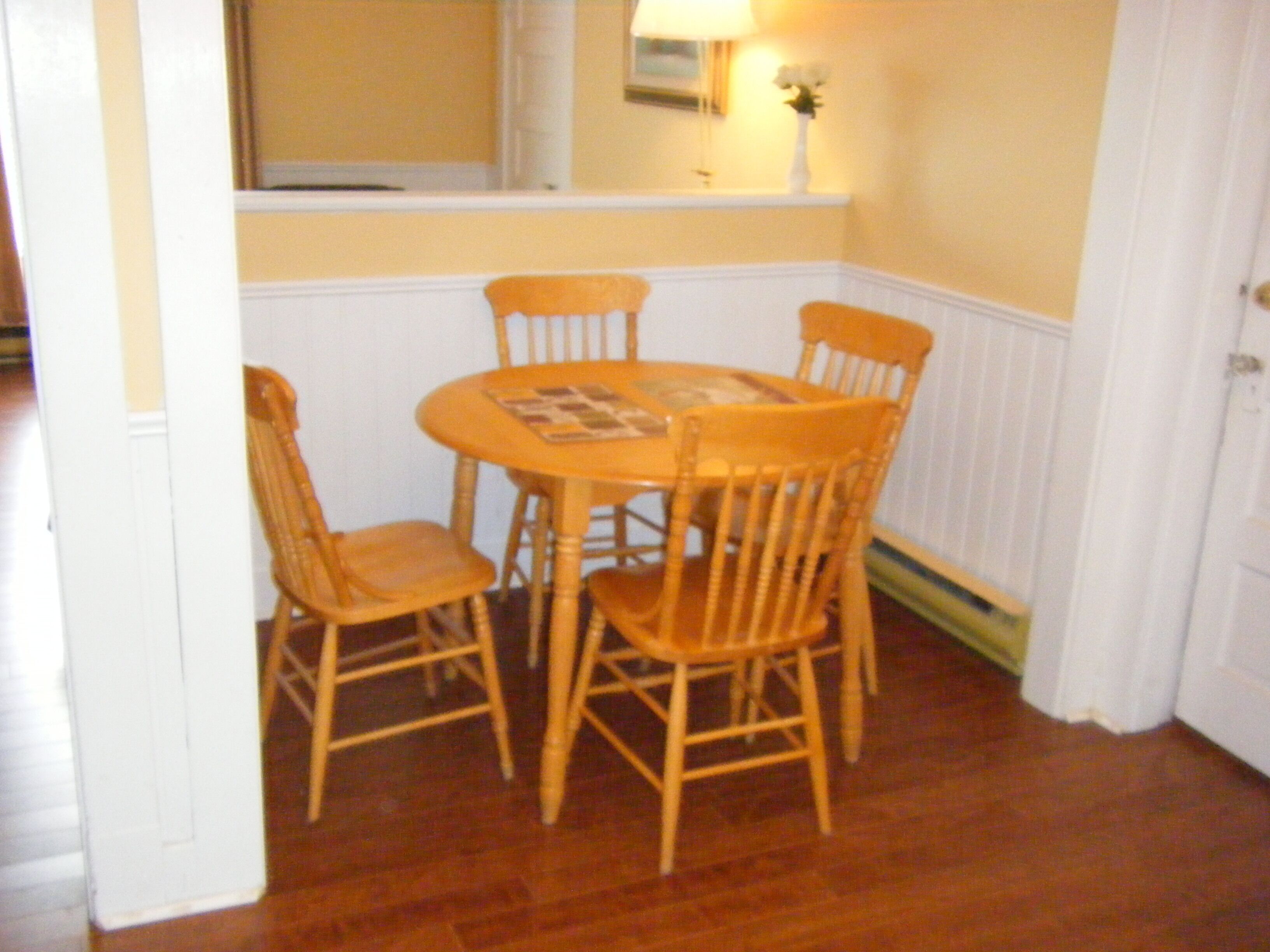 A dining area with a round table and four wooden chairs.