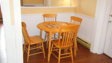 A dining area with a round table and four wooden chairs.
