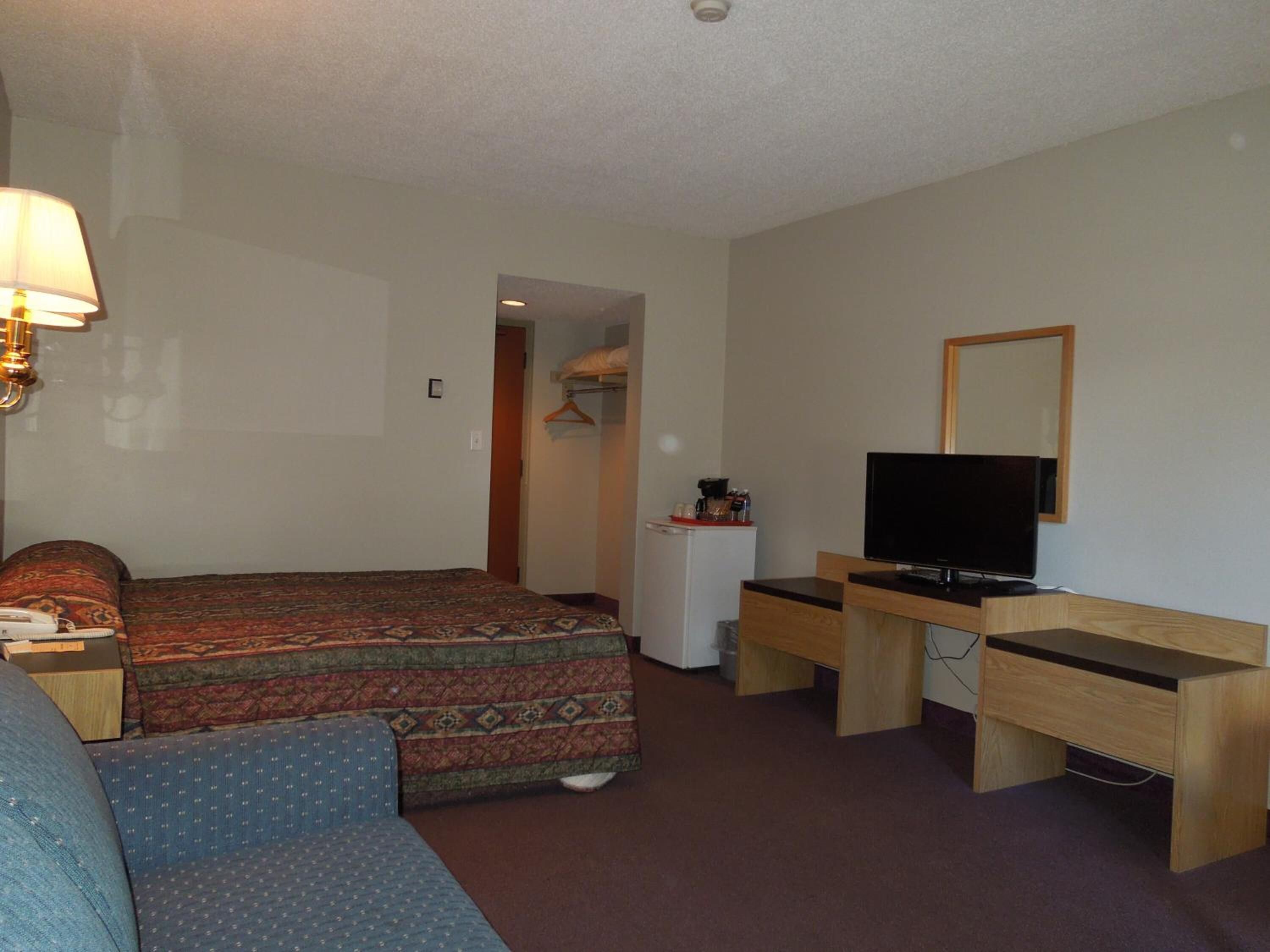Et hotelværelse med en seng, et skrivebord med en computer, et fjernsyn og en sofa.