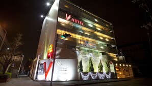 Un hotel moderno con un cartello ben visibile con la scritta 'HOTEL', un'area reception ben definita e una scalinata che conduce all'ingresso.