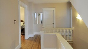 A hallway with a wooden floor, white walls, and a white door at the end. - Glory Guest Suites, Downtown Moncton (Moncton)