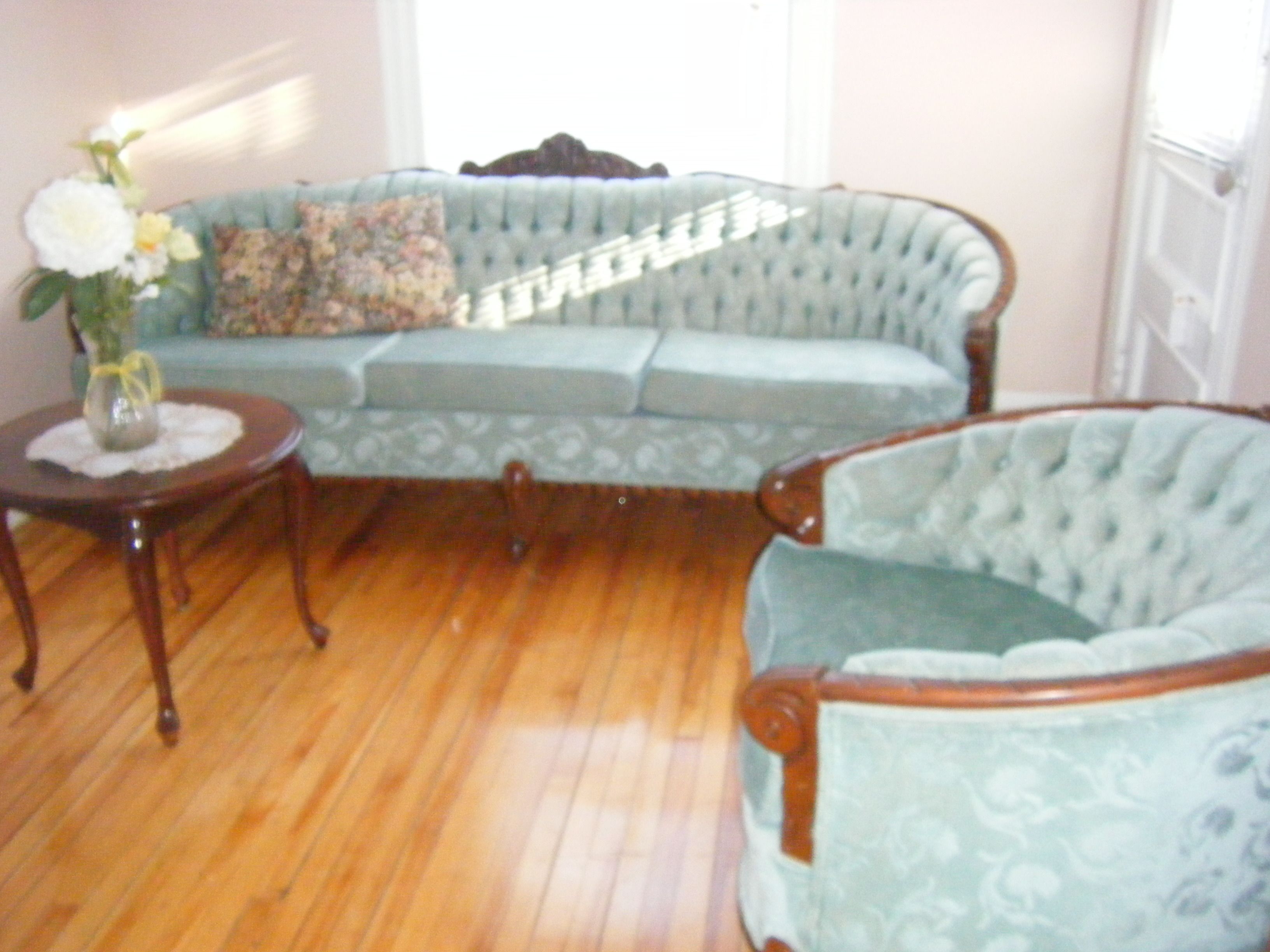 A room with a light blue patterned sofa, a wooden coffee table, and a floral arrangement on the table.