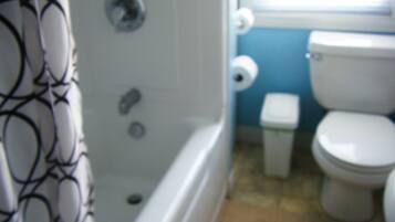 Un baño con bañera, inodoro y cortina de ducha.