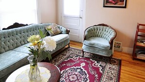 A living room with a light blue sofa, a patterned rug, and a small table with a vase of flowers. - Glory Guest Suites, Downtown Moncton (Moncton)