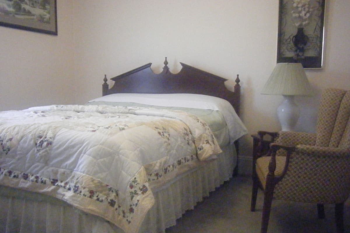 A bedroom with a bed, a chair, and a lamp.