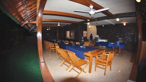 A dining area with a long table, wooden chairs, and ceiling fans. - Tulamben Wreck Divers (Tulamben)