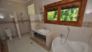 A bathroom with a bathtub, toilet, shower, and sink. - Tulamben Wreck Divers (Tulamben)