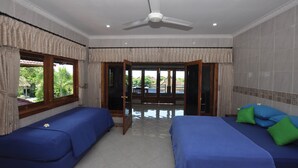 A hotel room with two beds, a ceiling fan, and a view of the outdoors. - Tulamben Wreck Divers (Tulamben)