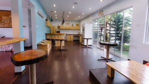A modern kitchen with wooden cabinets, a central island, and a large window with a view of trees. - Westwood Highland - Hostel (Kampung Raja)