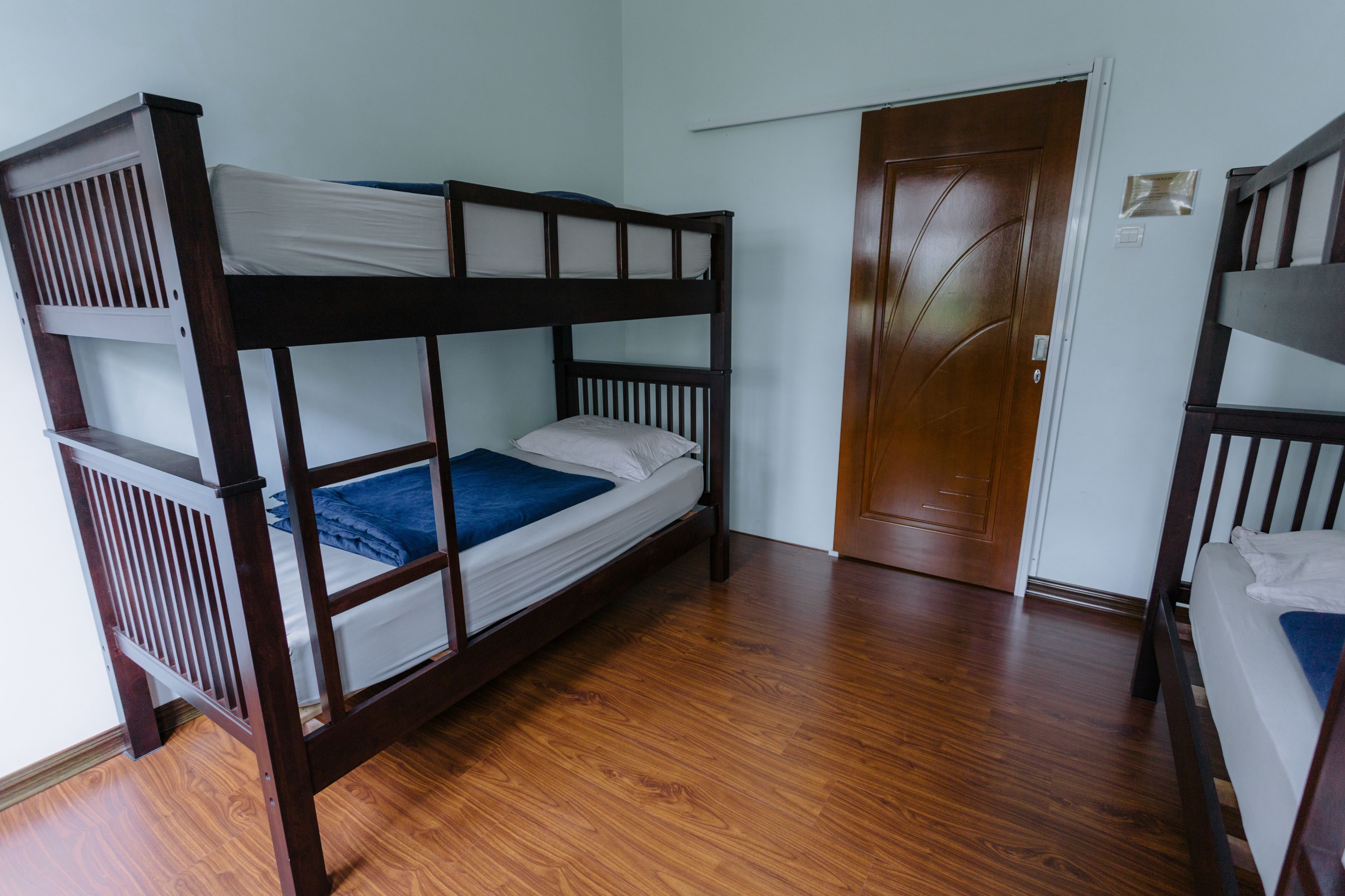 Habitació amb lliteres, terra de fusta i una porta.
