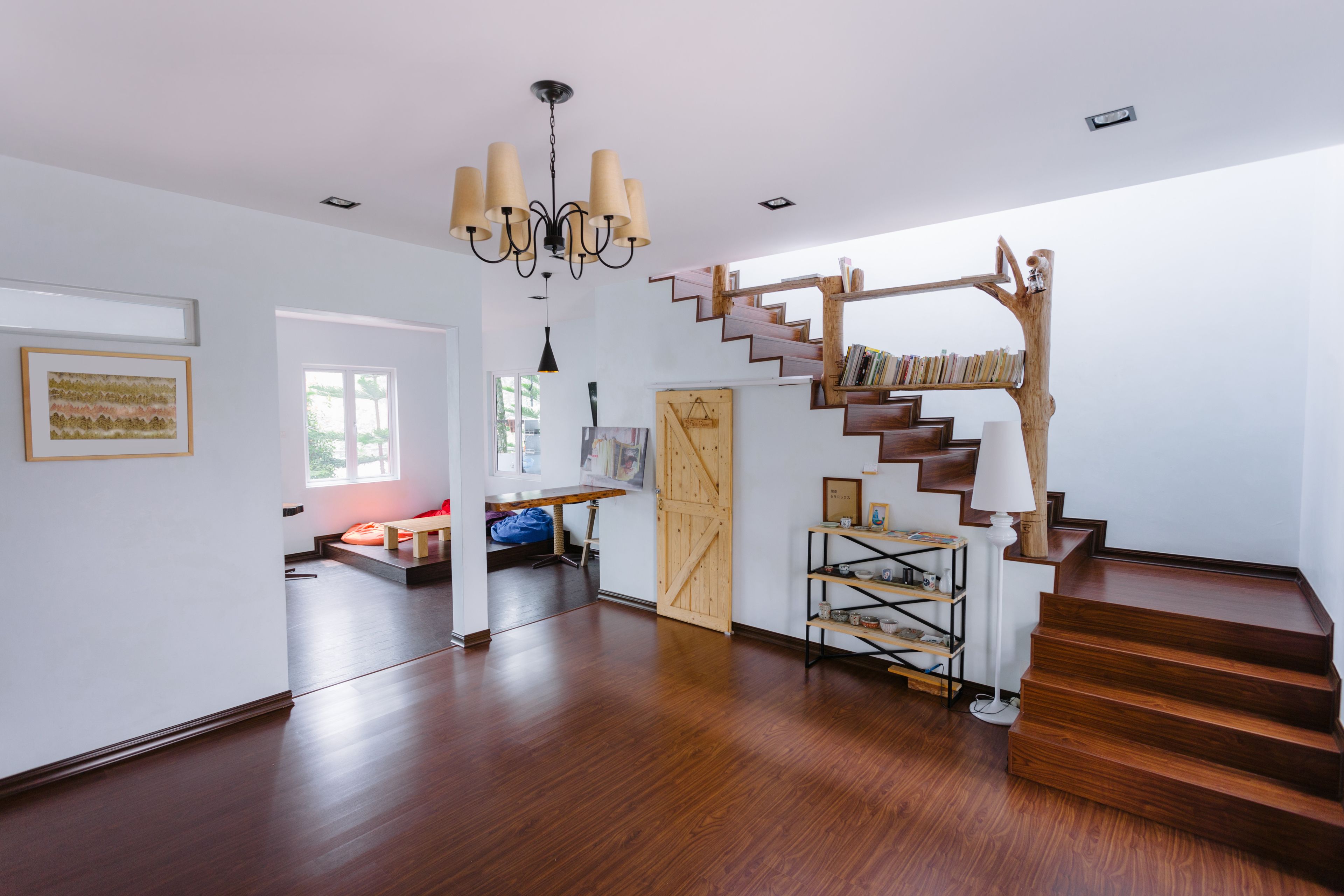 Amplia habitación con una escalera de madera, un candelabro y una estantería.