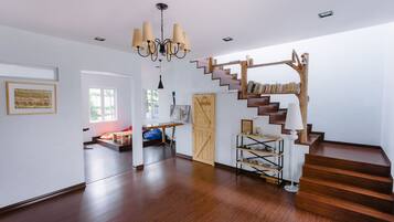 Amplia habitación con una escalera de madera, un candelabro y una estantería.