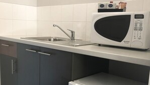 A kitchen with a microwave, sink, and a compact refrigerator. - Coro Club Motel (Griffith)