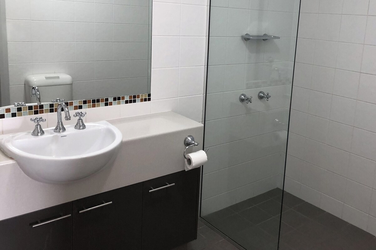 A bathroom with a white sink, a mirror, and a glass shower enclosure.