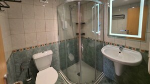Un baño con cabina de ducha de vidrio, inodoro y lavamanos.