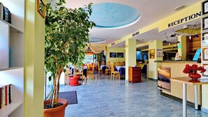 Un área de recepción con mostrador, sillas y una planta en maceta.
