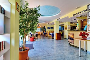 A hotel reception area with a reception desk, a potted plant, and a reception sign. - Bora Bora (Nessebar)