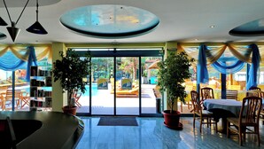 Un vestíbulo de hotel con mostrador de recepción, zona de estar y plantas en macetas.
