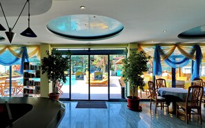 A hotel lobby with a reception desk, seating area, and potted plants. - Bora Bora (Nessebar)